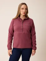 Canguro de sherpa color bordó, con cuello alto y cierre frontal parcial. Presenta un bolsillo con cierre en el pecho y bolsillos laterales, confeccionado en tejido de textura suave y abrigada.