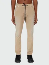Jean tipo jogg de Diesel, modelo Krooley, en color beige con efecto desgastado. Presenta cintura elástica con cordón de ajuste negro, cierre frontal y diseño de cinco bolsillos.