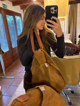 Bolso amplio marrón de gamuza con manijas de cuero, bolsillos laterales con clip, cierre posterior y bolsillo interno.
