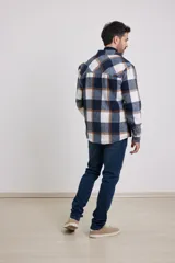 Sobrecamisa de hombre con diseño a cuadros en tonos marrón, beige y blanco. Confeccionada en tejido peludito suave, con cuello clásico, cierre frontal con botones, bolsillo superior y mangas largas con puños abotonados.