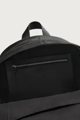 Mochila de cuero negro con compartimento principal y bolsillo frontal, ambos con cierre de cremallera. Incluye asa de mano superior, correas de hombro ajustables y parte posterior acolchada con banda de sujeción para equipaje.