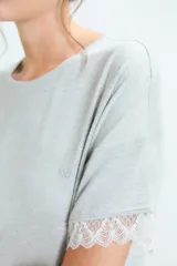 Pijama de dos piezas en color gris melange, compuesto por una remera de manga corta con detalles de encaje en los bordes y un pantalón de corte recto con cintura elástica y detalle de encaje en la pretina.