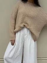 Sweater color beige con cuello redondo y diseño de trenzas en relieve.