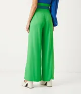 Pantalón de lino verde, modelo palazzo, con cintura alta, pliegues frontales y un cinturón bordado en tonos de verde y azul.