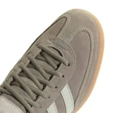 Championes adidas Handball Spezial inspirados en el modelo de 1979, confeccionados en gamuza gris topo con las clásicas tres tiras y refuerzo de talón en tono claro, inscripción lateral en letras doradas y suela de goma de tipo caramelo.