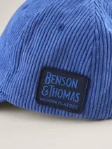Gorra tipo baseball confeccionada en pana color azul marino, con parche rectangular lateral que incluye el logo de la marca Benson & Thomas.