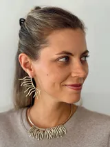 Aros colgantes dorados con forma de sol estilizado.