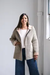 Tapado de paño con capucha, color beige, con cierre frontal, bolsillos laterales y puños vueltos en tono más claro.