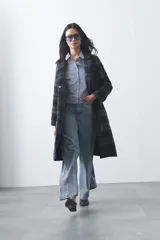 Tapado largo de corte recto con diseño de cuadros en tonos beige y azul. Presenta solapas clásicas, cierre frontal con botones y bolsillos laterales amplios.