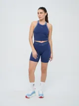 Top deportivo Umbro modelo Kia, color azul marino con detalles en gris en el cuello y sisas. Cuenta con logo estampado en el pecho y diseño de espalda deportiva.