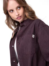 Camisa oversize de pana color bordó, de manga larga con puños abotonados, cierre frontal de botones y bolsillos dobles en el pecho.