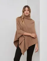 Poncho tejido color crema, con cuello polera y diseño trenzado diagonal en el frente. Presenta un corte asimétrico en el ruedo.