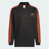 Camisa polo Adidas de manga larga en color negro, con cuello clásico y las icónicas tres tiras naranjas en las mangas. Presenta el logotipo del trébol bordado en naranja en el pecho con la inscripción 'Basketball'.