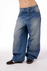 Pantalón de jean oversized de tiro bajo, color azul lavado, con grabado láser de la palabra "Blkmba" en el frente y "Worldwide" en la parte trasera.