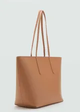 Bolso tipo shopper de tamaño grande, confeccionado en poliuretano con textura granulada. Cuenta con doble asa larga para llevar al hombro y cierre superior de cremallera.