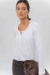 Remera manga larga blanca de algodón con spandex, corte ajustado al cuerpo y cartera con botones en el frente.