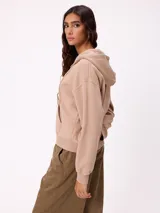 Canguro con cierre frontal y capucha, color gris con efecto desgastado. Presenta bolsillos laterales y logo bordado en el pecho.