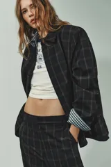 Blazer de corte recto con estampado de cuadros, cuello solapa y manga larga con hombreras. Presenta cierre frontal con botones ocultos bajo solapa y bolsillos delanteros con solapa.