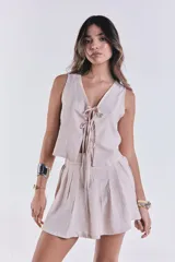 Chaleco color beige con escote en V y lazo de ajuste en el frente.