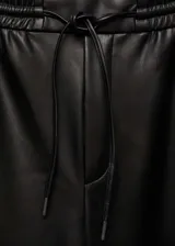 Pantalon tipo jogger de cuero sintético negro, con cintura elástica y cordón ajustable. Presenta un diseño de corte crop y costuras horizontales en la zona de las rodillas.