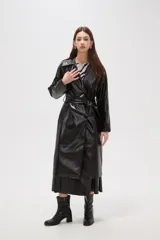 Trinchera de eco-cuero en color bordó, con diseño de doble botonadura, solapas amplias y cinturón ajustable en la cintura. Presenta mangas largas con detalles en los puños y bolsillos laterales.