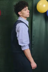 Mono largo de color negro con cierre frontal de botones vintage de distintos colores. Presenta un diseño sin mangas, con bolsillos laterales y una cinta para herramientas en la parte trasera.