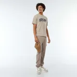 Pantalón de jogging color beige con bolsillos laterales y tobillos ajustados.