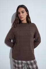 Sweater de punto gris con cuello a la base y diseño de trama geométrica en relieve. Presenta un calce relajado con mangas largas y puños tejidos.