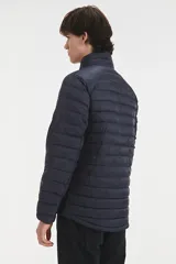 Campera puffer de color azul oscuro, con diseño acolchado horizontal, cierre frontal completo y cuello alto. Cuenta con bolsillos laterales con cierre y mangas largas.