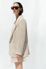 Blazer color crudo con diseño troquelado, cuello solapa, manga larga y bolsillos delanteros de plastrón.