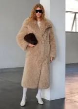 Campera larga de abrigo con textura peluda tipo corderito sintético, en color tostado, con solapas anchas y mangas largas.