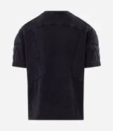 Remera boxy de algodón color negro con efecto desteñido, cuello redondo, mangas cortas y hombreras estructuradas con recortes y pespuntes.