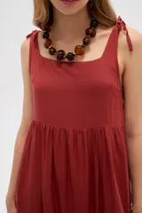 Vestido midi negro de viscosa con cuello cuadrado y tirantes finos ajustables con lazo en los hombros, de corte holgado y diseño fluido.