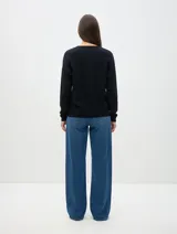 Buzo de tejido de punto color negro, con cuello redondo, manga larga y corte relajado. Presenta puños y ruedo acanalados.