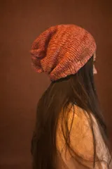Gorro tipo beanie tejido en lana gruesa de color salmón, con detalle de etiqueta de cuero en el lateral.