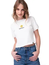 Remera crop blanca de algodón y poliéster reciclado, de manga corta y cuello redondo. Presenta un estampado frontal con una carita feliz y el texto "Caterpillar".