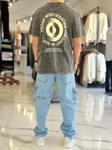 Remera oversize de color celeste con efecto gastado acid wash, mangas cortas y cuello redondo. Cuenta con un gran estampado circular en la espalda con la frase "Not all those who wander are lost" y texto adicional debajo.