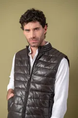 Chaleco acolchado de cuero color marrón, con diseño matelasseado horizontal, cierre frontal y cuello alto.