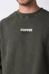 Buzo de cuello redondo en algodón rústico con efecto de lavado gastado, corte oversize y estampa frontal pequeña con texto.