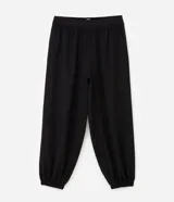 Pantalón de corte aladín confeccionado en crepé, de tiro alto con cintura elástica en la parte trasera. Presenta piernas anchas con volumen tipo globo que se estrechan en los tobillos mediante puños elásticos. Incluye bolsillos laterales funcionales.