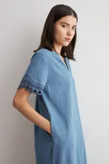 Vestido midi de jean azul, de corte holgado y diseño en capas con volados, escote en V, mangas cortas con detalles bordados en los puños.
