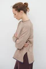 Buzo de tejido de punto color beige, con corte relajado, cuello redondo y mangas largas. Presenta detalles de terminaciones en color azul marino en los puños y en el ruedo inferior.