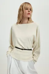 Jersey de punto negro con cuello barco y mangas largas amplias. Presenta un diseño ajustado en la cintura con un cinturón fino integrado que incluye una hebilla metálica dorada.