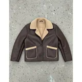 Campera gamulán de ecocuero marrón con forro y detalles de corderito en cuello, solapas y bolsillos. Cuenta con cierre frontal de botones y dos bolsillos aplicados.