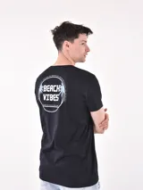 Remera negra de corte oversized con estampa circular en el pecho con la frase "Beach Vibes".