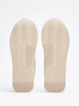 Zapatillas Tommy Hilfiger color crema con detalles en beige y dorado. Confeccionadas en poliéster con paneles mixtos y logo bordado en la lengüeta y el talón.