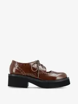 Zapato tipo guillermina con cordones, confeccionado en cuero color marrón, con detalles de perforaciones decorativas y suela de plataforma negra.