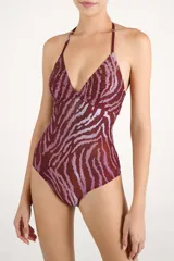 Malla enteriza con estampado animal print tipo cebra en tonos bordó y rosado, con diseño triangular y tirantes ajustables al cuello. Presenta detalles de tachas aplicadas en el busto.