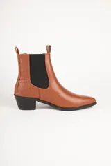 Bota de cuero color marrón con elástico negro en los laterales, caña baja, punta fina y taco cuadrado.