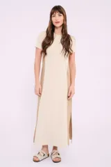 Vestido midi de corte recto y diseño bicolor, con frente en color crema y laterales en color beige. Presenta cuello redondo, mangas cortas y aberturas laterales en el ruedo.